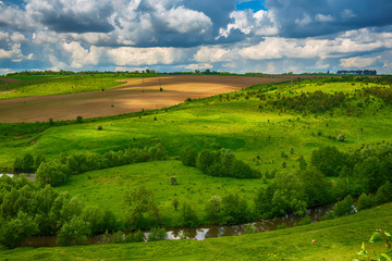 Fototapeta na wymiar Rural landscape with fields, waves and blue sky with clouds, spring seasonal natural background