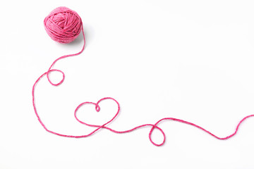 Pink thread, heart and tangle on white background