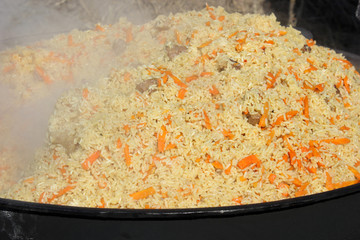 Hot halal rice pilaf in a cauldron on fire.