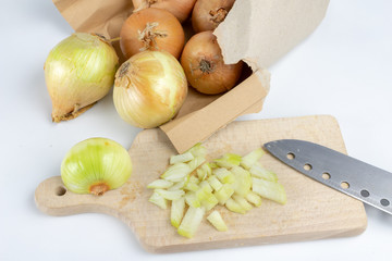 Onion on a chopping board on a white kitchen table. Vegetables for preparing dishes in the home kitchen.