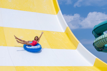 Excited teenage girl enjoys summer vacation in water park riding blue inflatable float