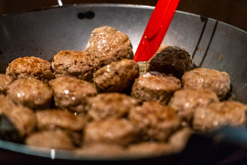 Round Pork Cutlets Being Baked for Some Burgers for  Wedding Meal on Pan with Blue Flames Under it
