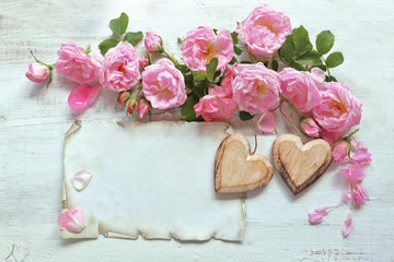 Roses with paper , heart on wooden background 