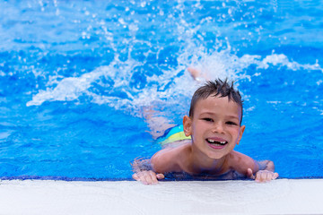 Smiling boy have fun splashing water in swimming pool