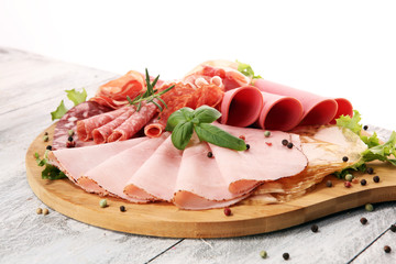 Food tray with delicious salami, pieces of sliced ham, sausage and salad. Meat platter with...