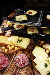 Fototapeta na wymiar Delicious traditional Swiss melted raclette cheese served in individual skillets with salami.