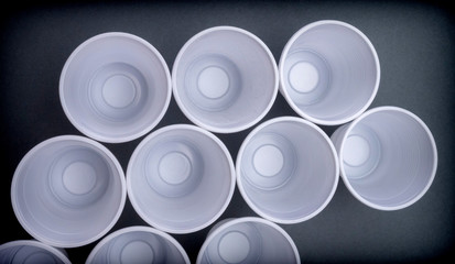Several white plastic glasses seen from above isolated in black background