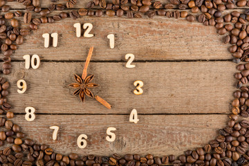 Decorative clock with wooden numerals and arrows made of cinnamon sticks, showing 4 o'clock, on a wooden background and a frame of coffee beans. Kitchen, advertising, banner, Copy space, flatly.