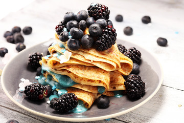 Delicious Tasty Homemade crepes or pancakes with blackberries,blueberries and blue spirulina nicecream.