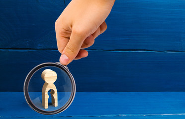 Magnifying glass is looking at the wooden figure of a woman with a void inside in the shape of a...
