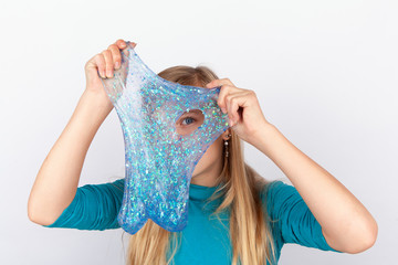 Funny girl holdin a glitter slime in front of her face and looking through its hole.