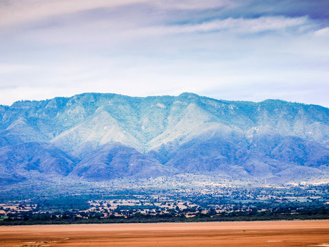 Mexican landscape with dry Sayula lagoon and wet sand with a mountain range and vegetation in the background, cloudy day with abundant clouds in the southern region of Jalisco, Mexico