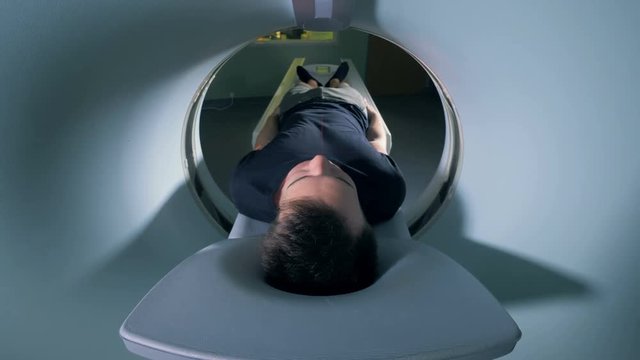 A man is getting scanned by a magnetic resonance imaging mechanism