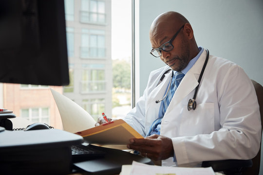Doctor writing on file