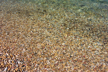 Pebbles texture diagonal covered by blue sea water