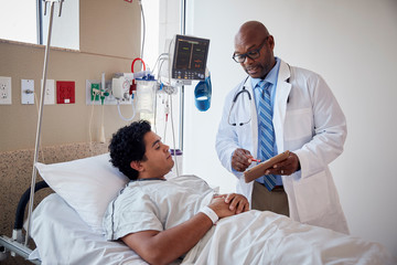 Patient talking to doctor while lying a hospital bed