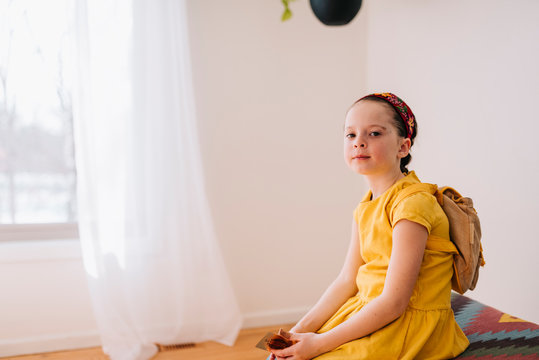 Portrait Of A Girl Sitting On A Stool Holding A Golden Gift Certificate