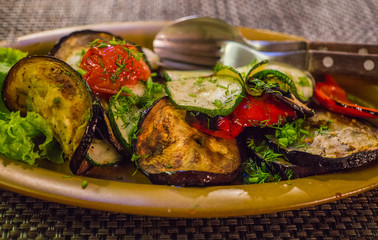 Grilled eggplants on a plate, together with vegetables.