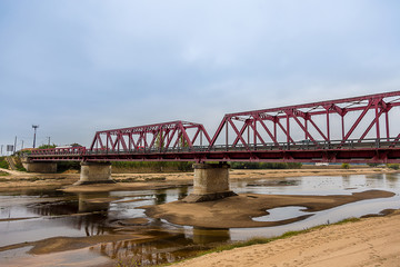 Fototapeta na wymiar Metallic Bridge over a Nearly Dry River under a Cloudy Sky
