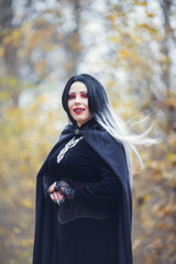 Portrait of vampire woman in black cloak with amulet