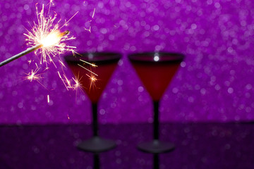 Martini glass on black glass background. Burning Bengal fire is the flame of Christmas. The new year is 2019.