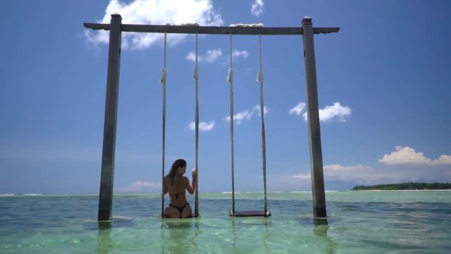A shot of woman relaxing on the swing inside the ocean