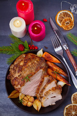 Baked ham with vegetables: carrots, onions, garlic and herbs. Christmas decorations. Dish for Christmas Eve. View from above, top studio shot