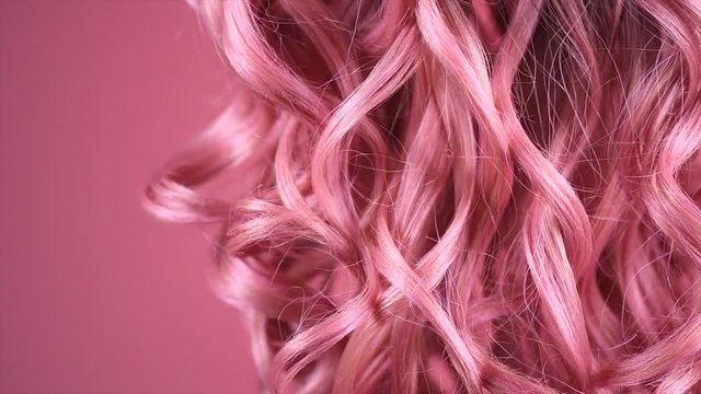 Hair. Beautiful trendy long curly pink hair closeup texture. Dyed wavy pink hair background. Coloring concept. Haircare. Slow motion 4K UHD video footage. 3840X2160