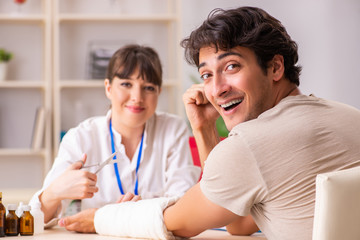Obraz premium Young man with bandaged arm visiting female doctor traumatologis