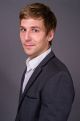 Portrait of young handsome businessman against gray background