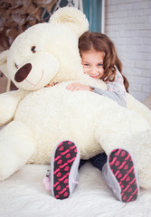 A child is hugging a big teddy bear. Happy girl hugging a soft toy.