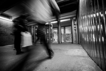 Entry in Kyiv underground with moving blurry people and bright station light. Photo with black and white vintage effect