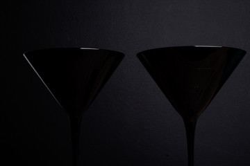 Black on black: two elegant balck glass martini glasses on black tablecloth and black background
