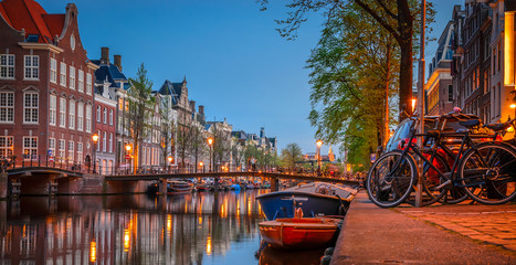 Traditional old buildings and boats at night in Amsterdam, Netherlands.