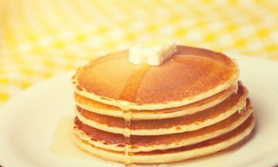Stack of Small pancakes in syrup on background