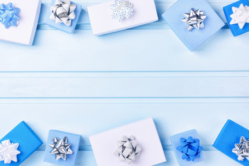 White and blue boxes lie on a light background. Gifts decorated with bows.