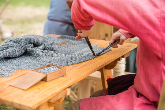 Artesano armero medieval trabajando en una cota de malla