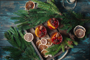 Homemade Christmas mulled red wine with spices, cinnamon and citrus fruit on rustic wooden...