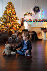 Ребенок ждет чудо в Новый год. С Новым годом! Счастливого Рождества! Елка с новогодними игрушками. Маленький мальчик возле елки с игрушками. 
