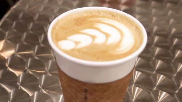Maple latte in a coffee shop, camera moving towards the drink on the table.