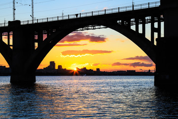 Silhouette of an arched railway bridge on a beautiful sunset on the Dnieper River in the city of Dnipropetrovsk (Dnipro, Dnepr, Dnepropetrovsk) Ukraine.