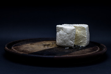 Brazilian minas white cheese on a wooden cutting board isolated in dark background