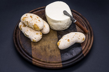 Cheese bread and brazilian minas white cheese on a wooden cutting board isolated in dark background