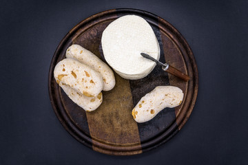 Cheese bread and brazilian minas white cheese on a wooden cutting board isolated in dark background