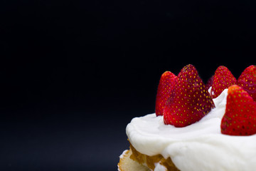 Organic strawberry cake with whipped cream isolated on a black background