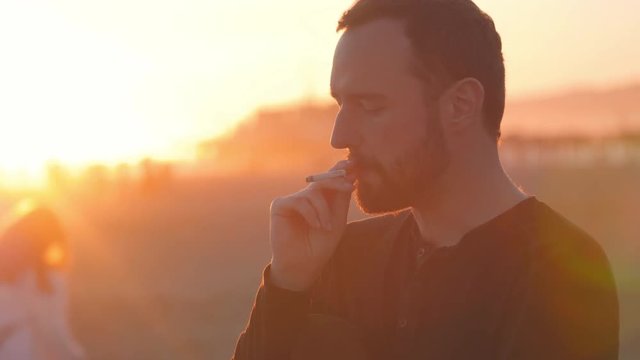 Contemplative man smoking cigarette at sunset