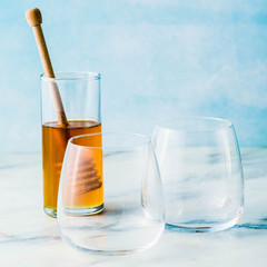 two empty glasses for dessert or drink and honey on a table on a blue background
