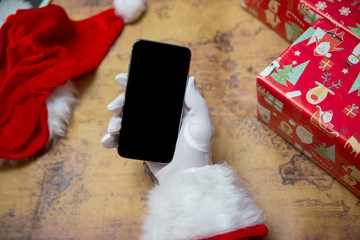 Santa Claus holding showing smart phone with blank space background, closeup image. Using wireless digital communications mobility technology equipment device.