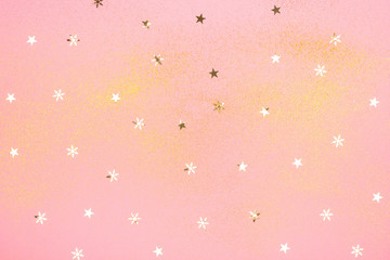 Beautiful light pink background with golden glitter and star shaped confrtti. Holiday decoration concept.