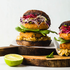 Gluten-free vegan burger made from portobello mushrooms with cutlets from potato and chickpea flour with caramelized onions, sprouts and baby spinach. Healthy fast food made from natural products